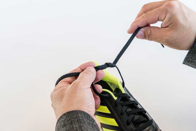 ②左右のひもを引っ張る前に、もう一度、くぐらせます。