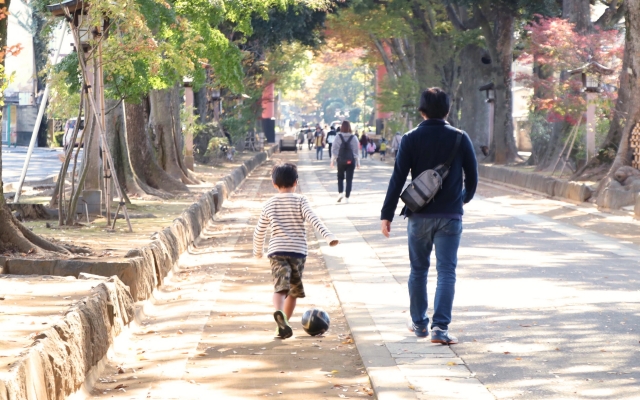 サッカーボールを蹴りながら歩く親子